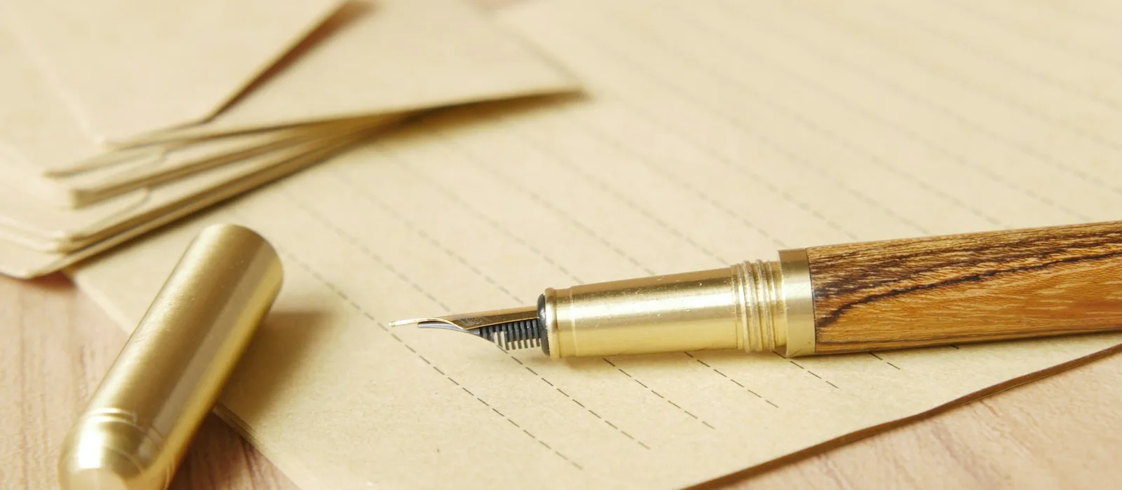 Une lettre, une enveloppe et un stylo sur une table en bois clair