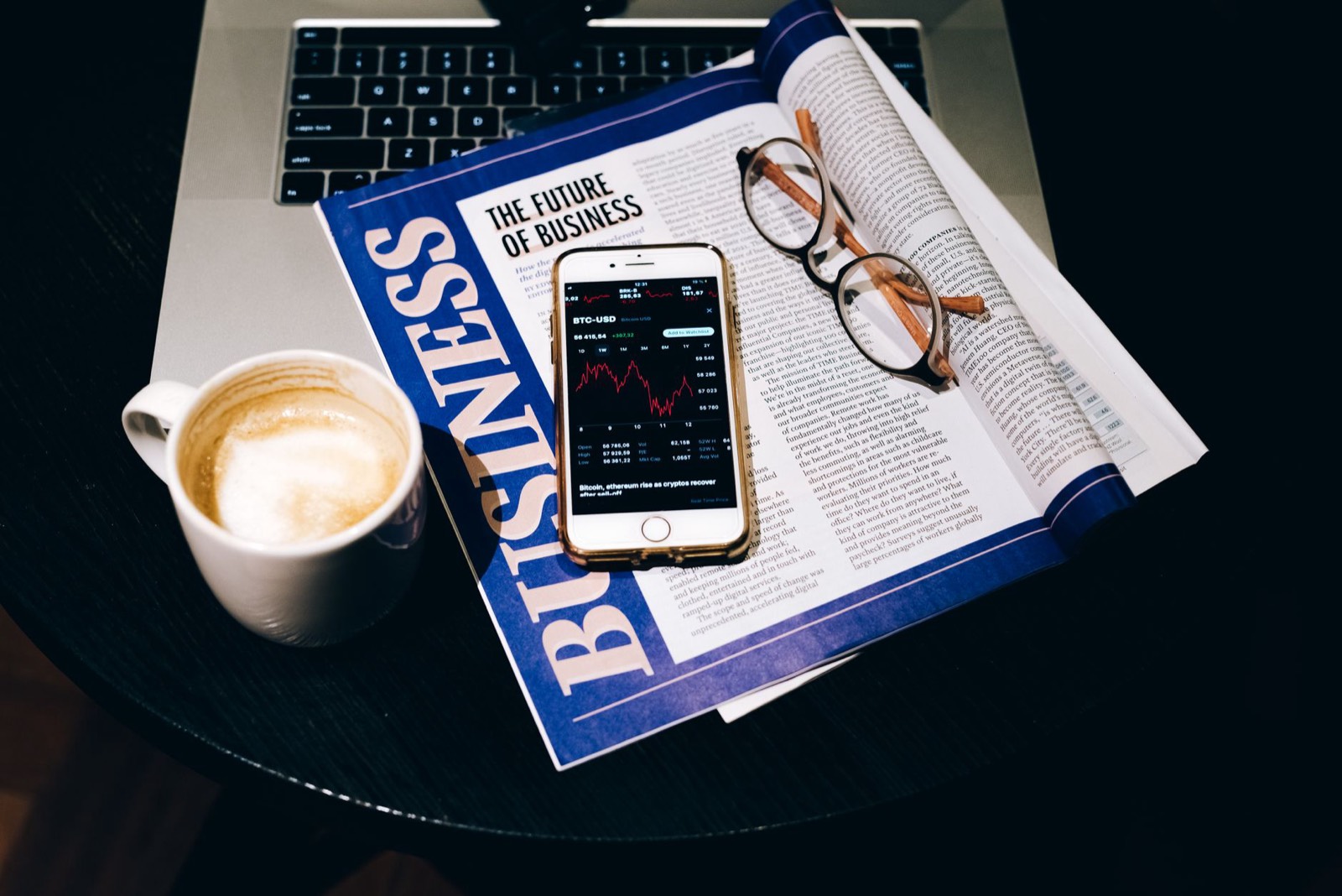 Ordinateur portable, journal et tasse de café sur un bureau, lecture de l'actualité crypto du matin