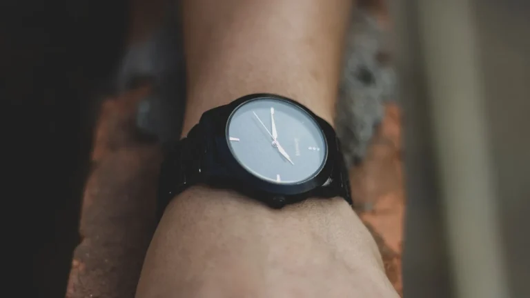Poignet portant une montre analogique noire à cadran bleu-gris