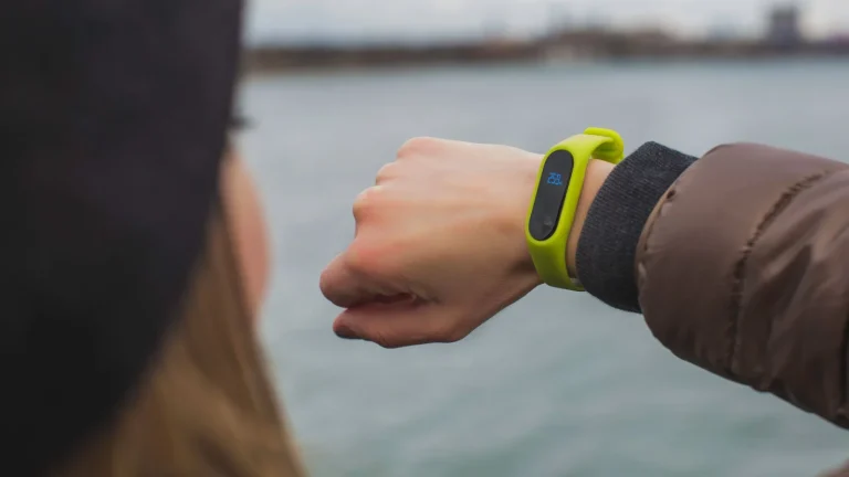Poignet portant un bracelet connecté vert dont l'écran affiche une valeur