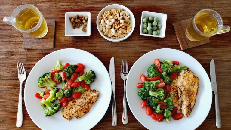 Deux assiettes équilibrées de poulet grillé, brocolis et tomates, avec des noix et du thé
