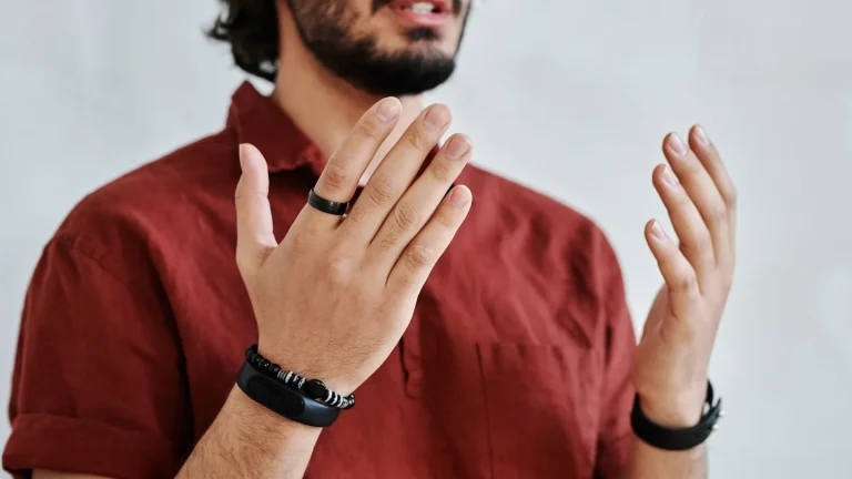 Main d'un homme portant une bague connectée et un bracelet de suivi sans écran
