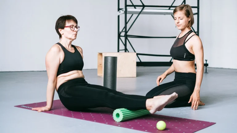 Deux femmes sur un tapis avec un rouleau de massage vert et une balle de massage