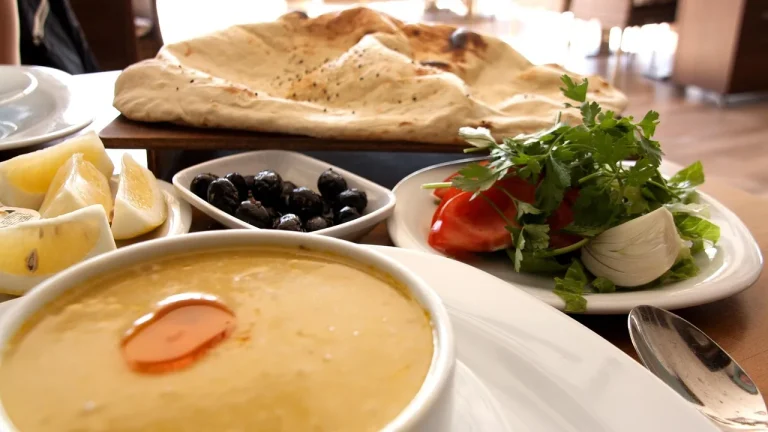 Soupe, assiette de crudités, olives et pain plat servis pour un dîner léger