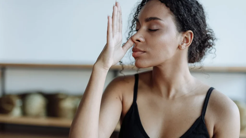 Femme les yeux fermés pratiquant une technique de respiration contrôlée, main devant le nez