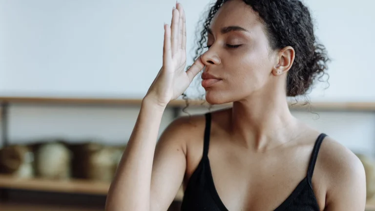 Femme les yeux fermés pratiquant une technique de respiration contrôlée, main devant le nez