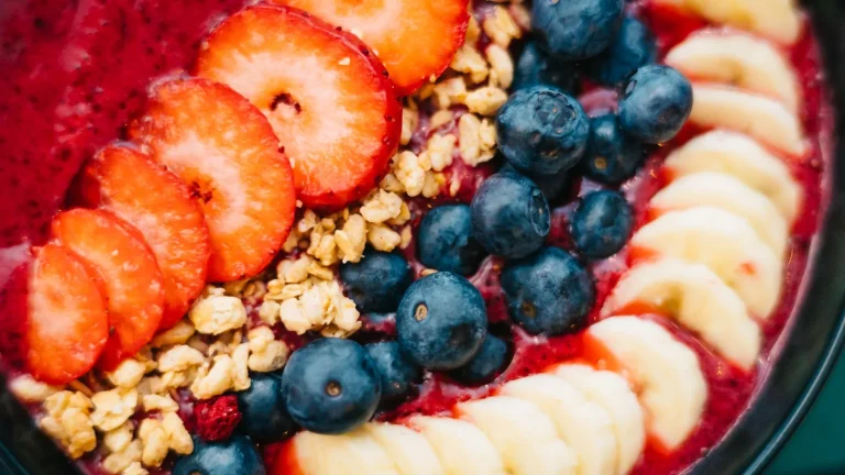 Bol de granola garni de fraises, myrtilles et rondelles de banane