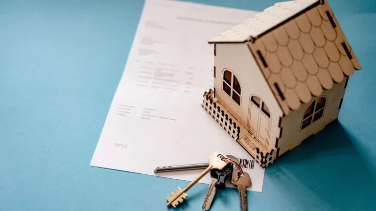 Maquette de maison en bois avec un trousseau de clés posée sur un contrat