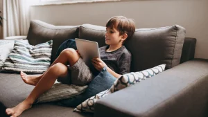 Enfant allongé sur un canapé avec une tablette numérique entre les mains
